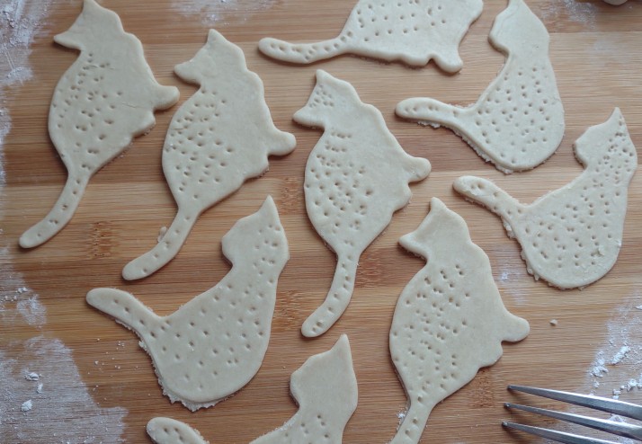 Rolled dough cut with cat-shaped cookie cutters.